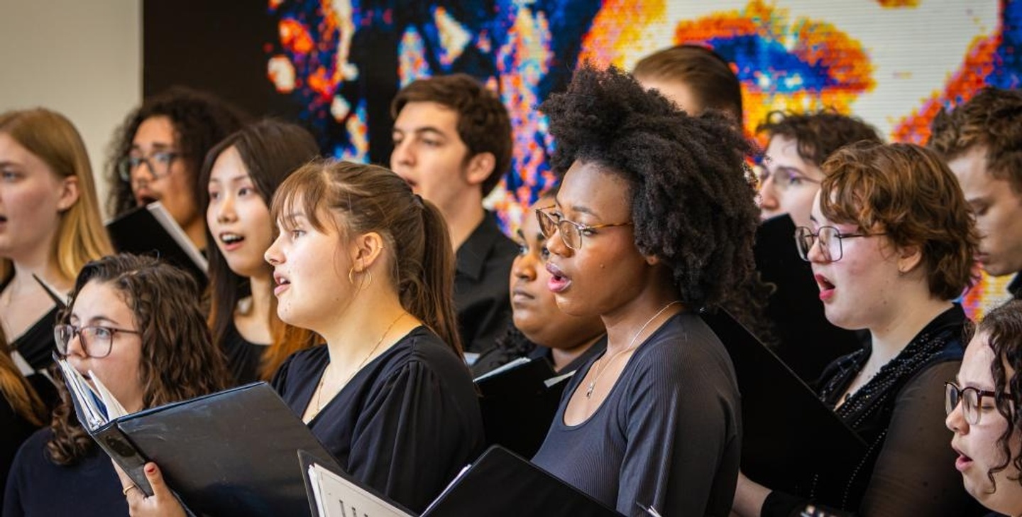 A choir is shown signing in front of artwork at the Kemper Art Museum.