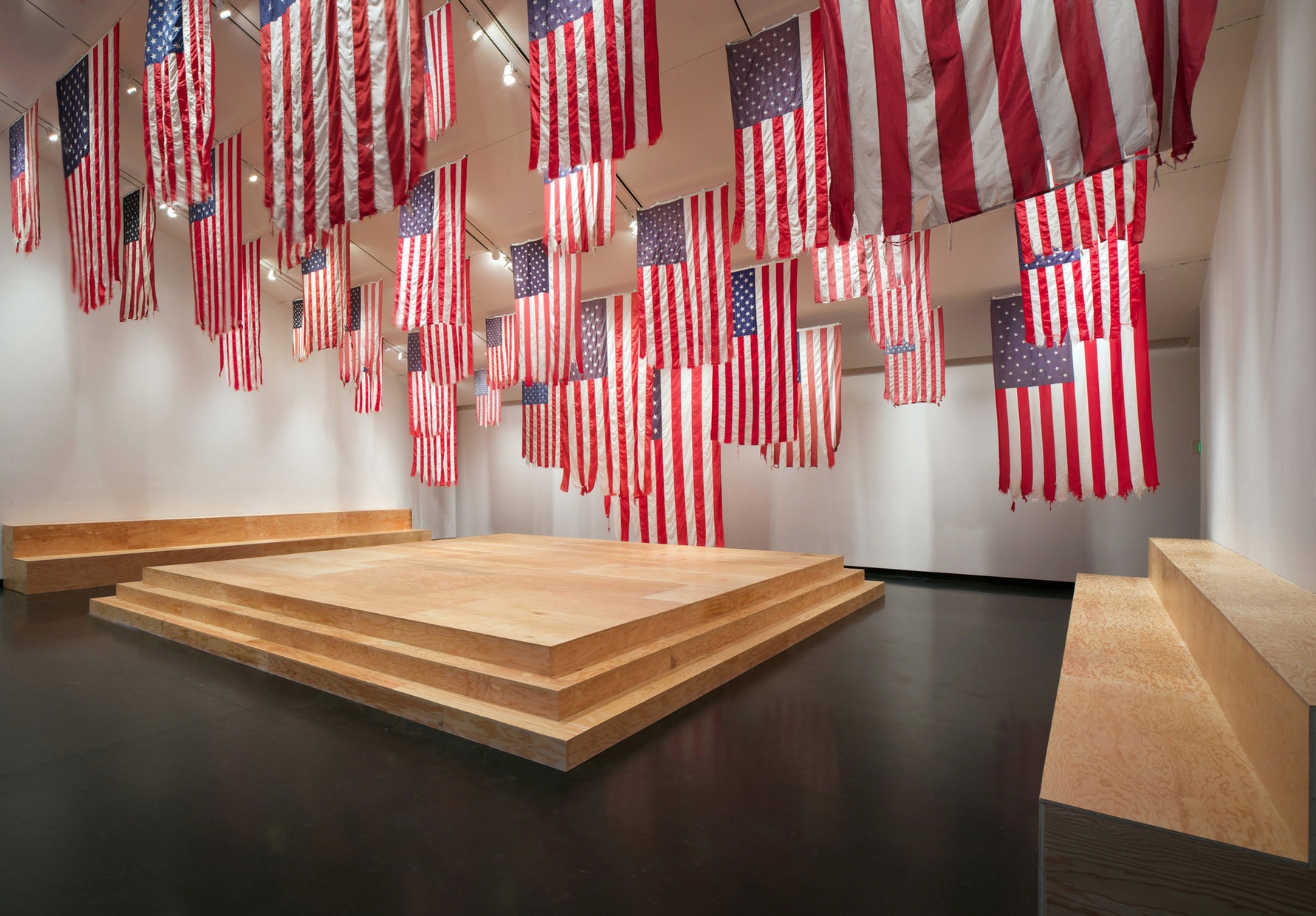 An empty room with white walls and American flags hanging from the ceiling.