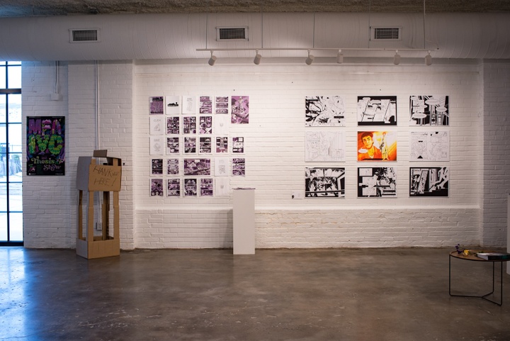 Gallery wall with two sets of comics pages displayed on a wall, plus a cardboard model that pairs with one of the comics.