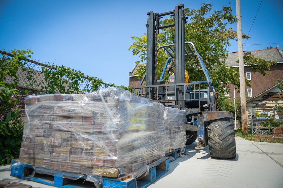 A palette of bricks is lifted by a forklift. 