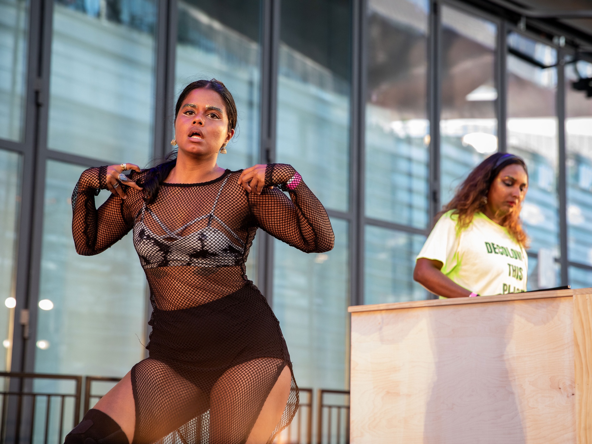 Woman DJing with another woman performing in front of her.