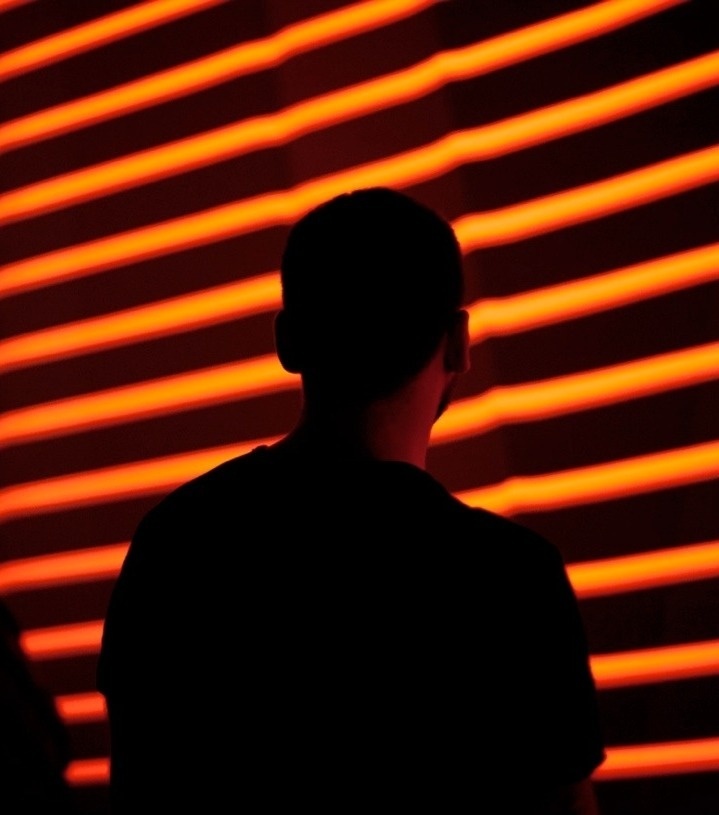 A person standing against the animated wall which shows repeated orange lines