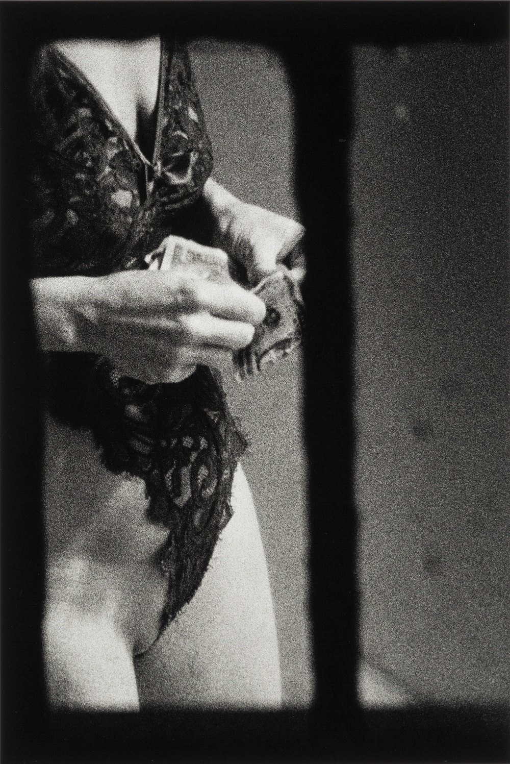 A black and white photograph, framed by a windowpane, of a woman’s torso dressed in lingerie and holding paper money in her hands.