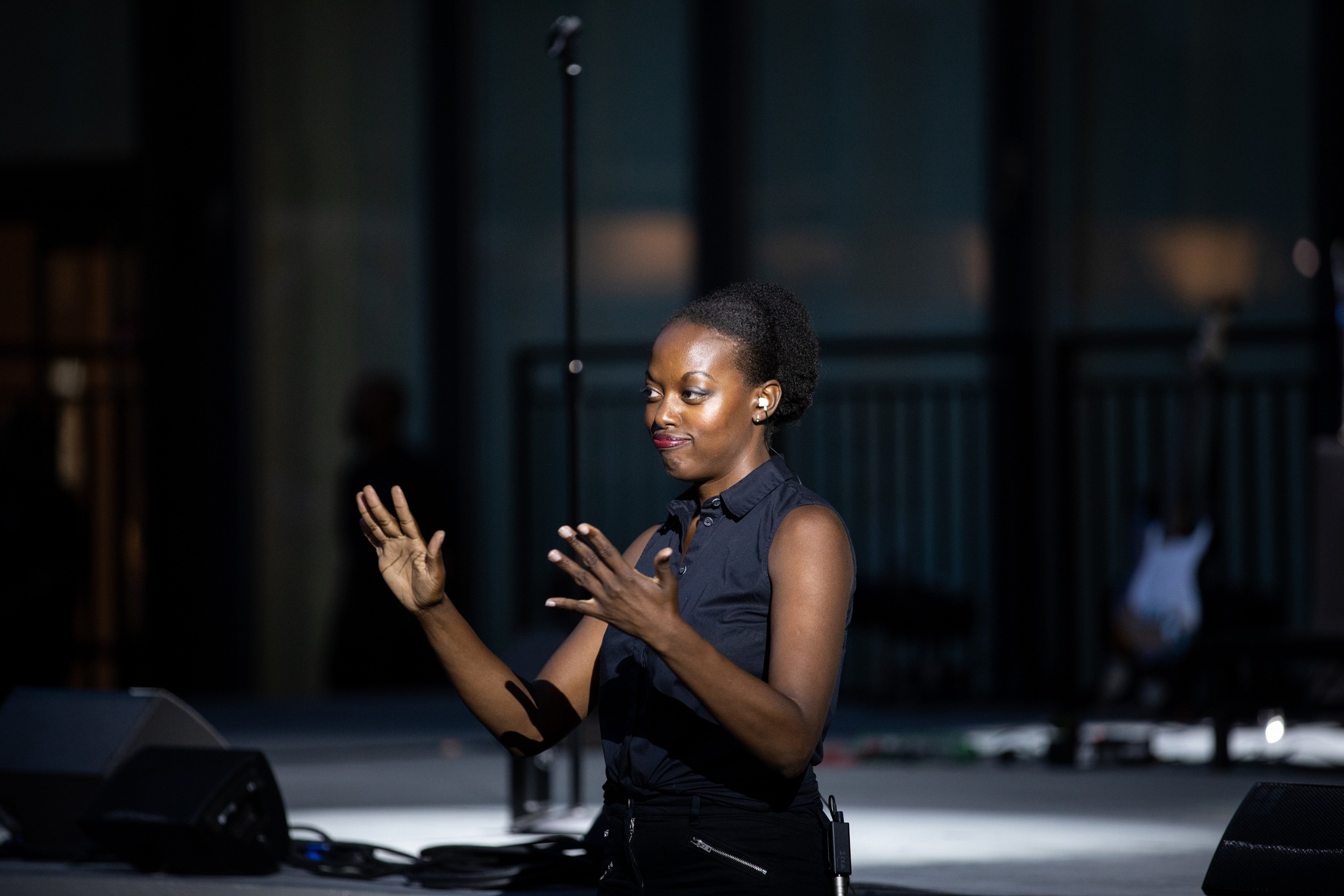 Woman signing on dramatically lit stage.