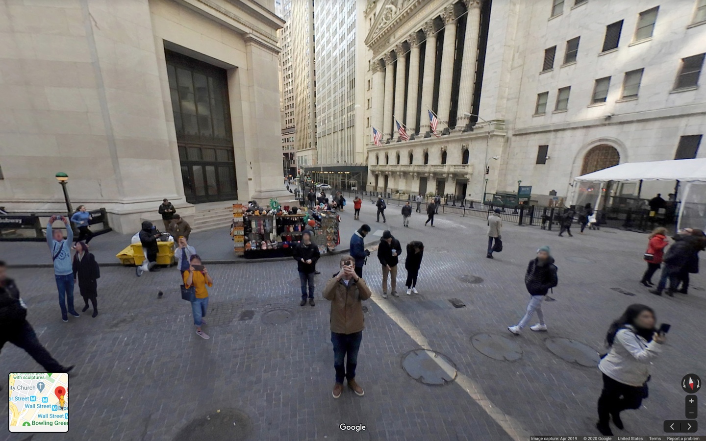 Screencap of Google Street View on a bricked street area with neoclassical federal buildings. Pedestrians walk along the sidewalks and in the streets. Several people are stopped, taking photos of the Google Street View camera with their phones.