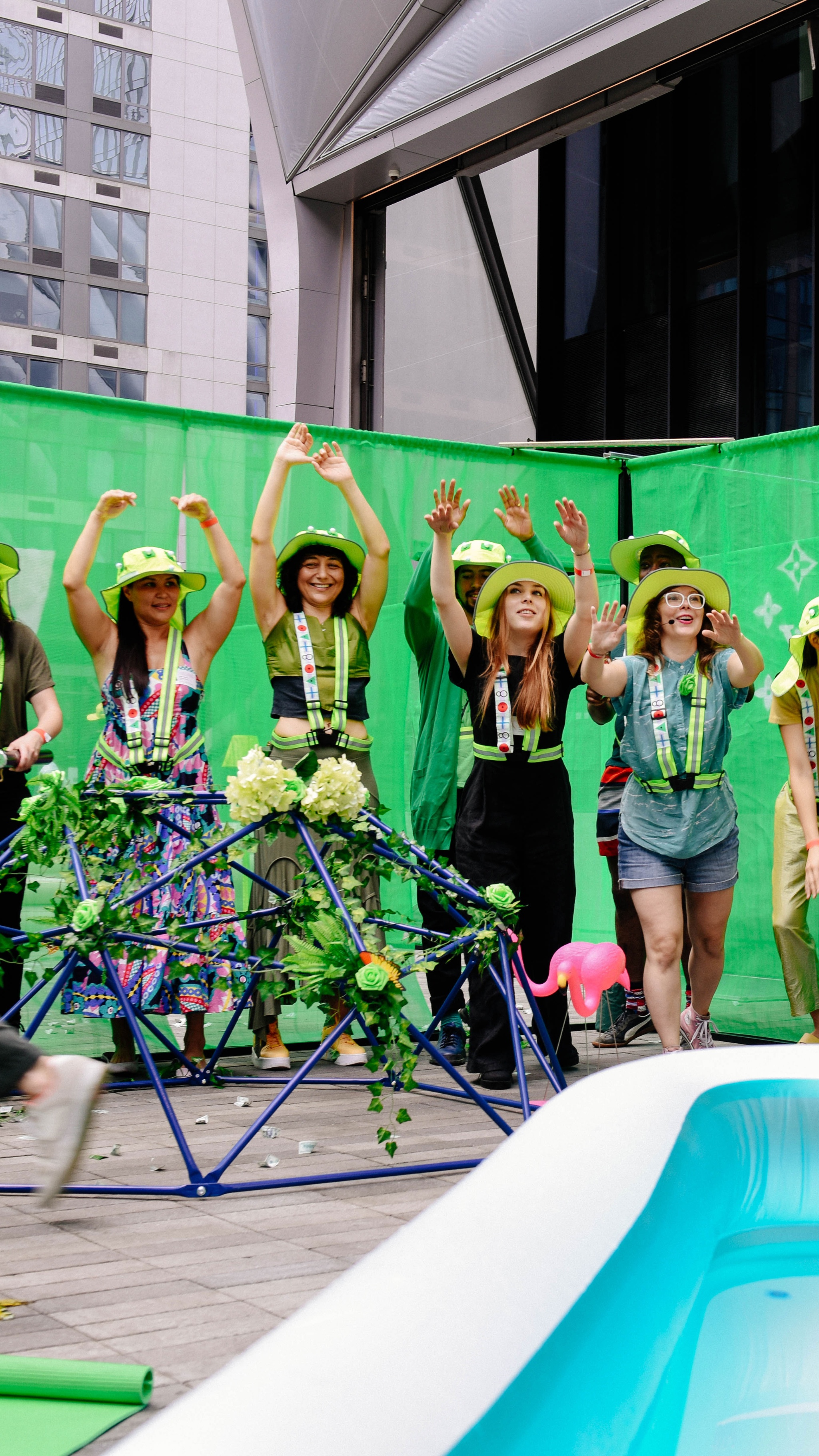 A group of participants in green hats, in front of a kiddie pool.