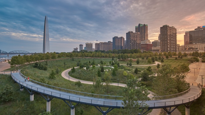 Wide-angle shot of the Arch grounds from the north, showing the Arch, walkways and green spaces, and a few buildings in downtown.