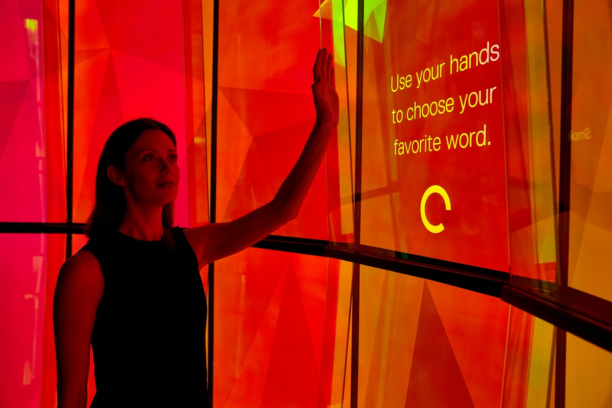 Woman interacting with The City Cave experience, using their hand to choose their "favourite word"