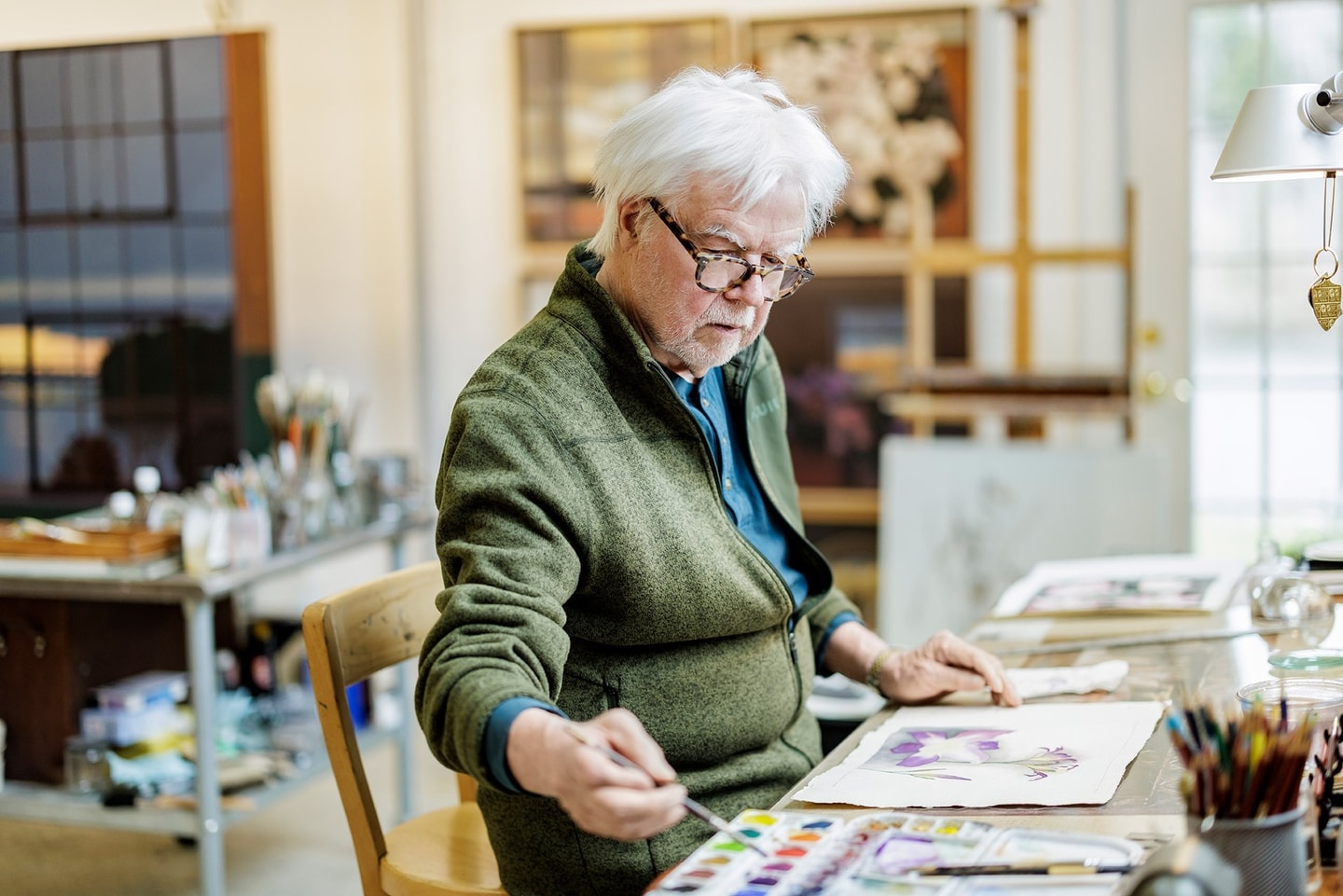 Moore in a green sweater painting in his studio
