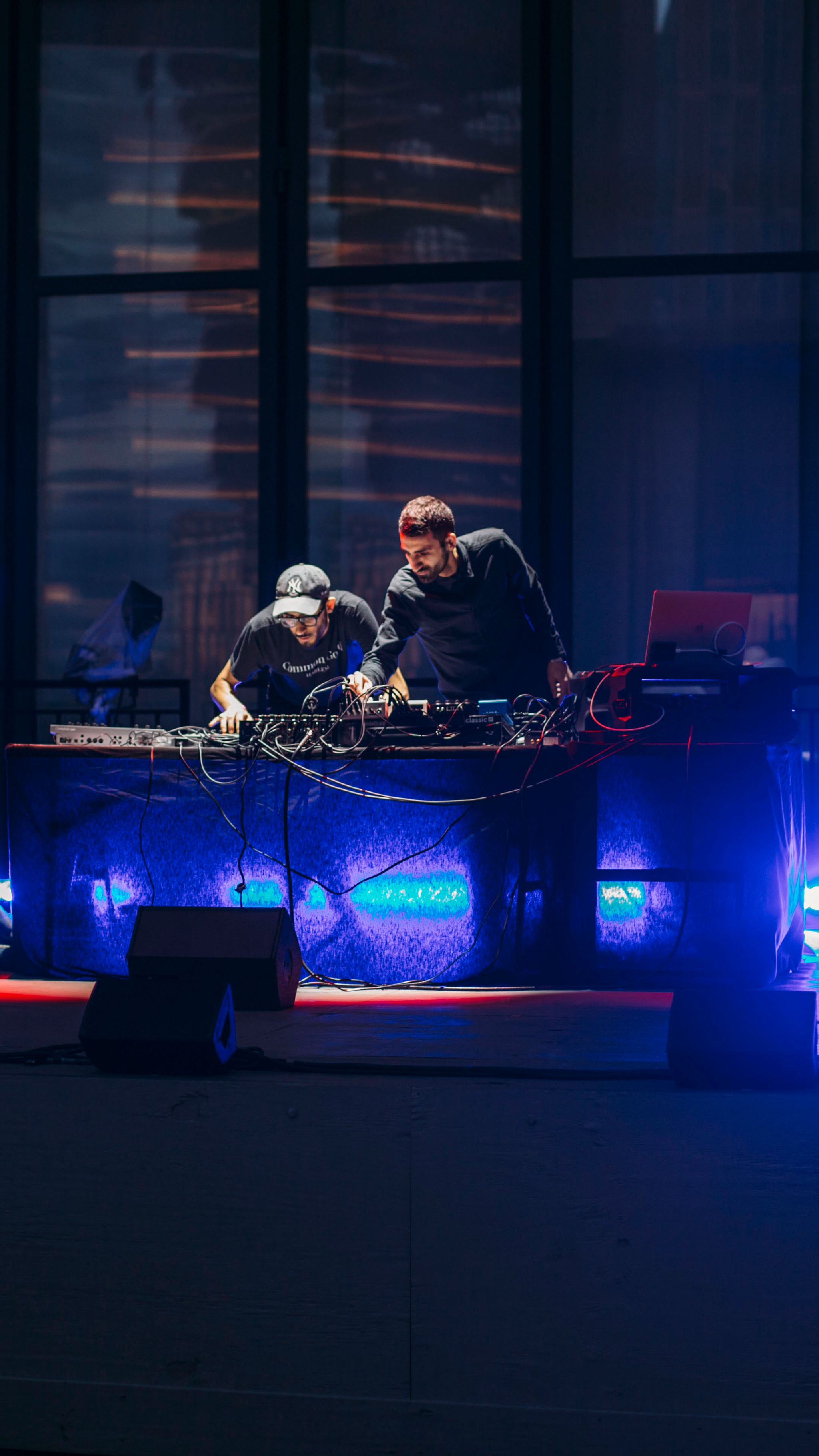 Two men behind an electronic DJ set up.