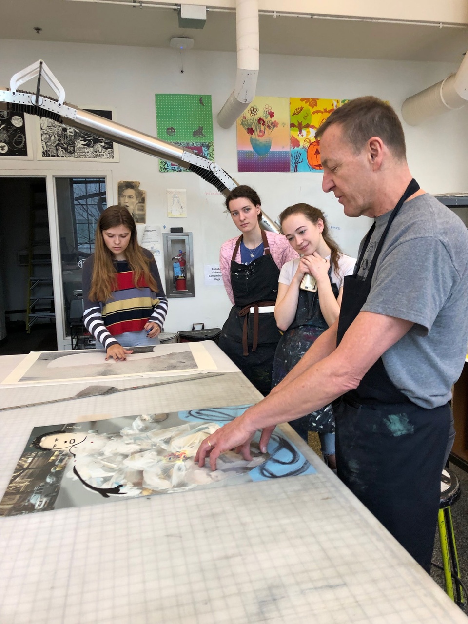 David gesturing to a print in front of him on the table while 3 students look on.
