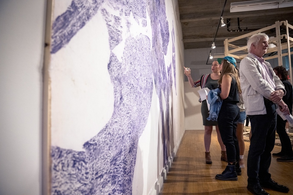 Visitors in front of Anna Schenker's large tree rubbing on muslin artwork