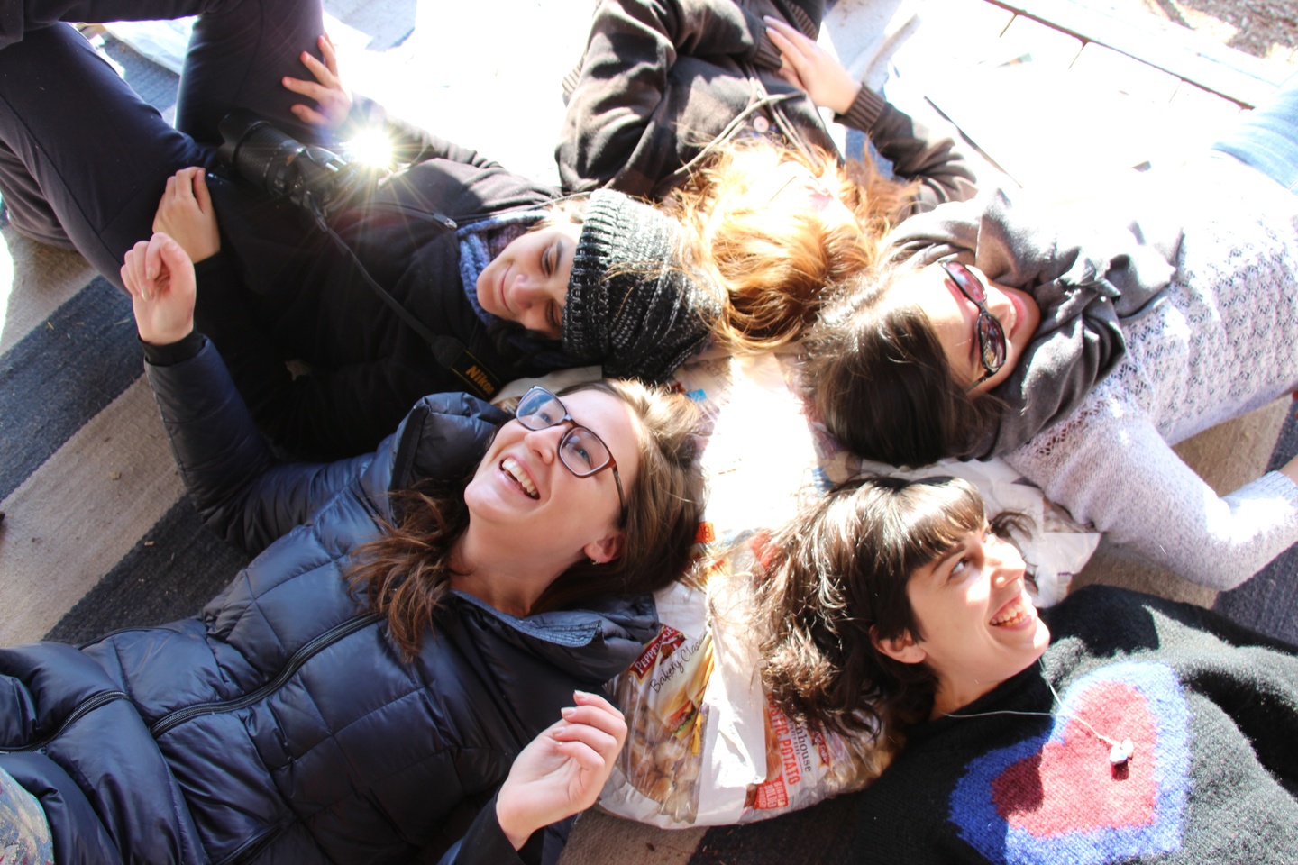 A group of people are smiling, with their heads laying on a bag.