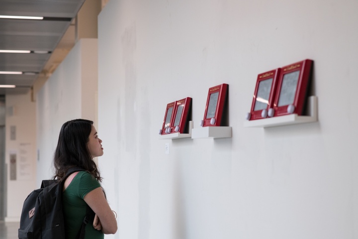 A visitor in front of 4 etch-a-sketch artworks on display