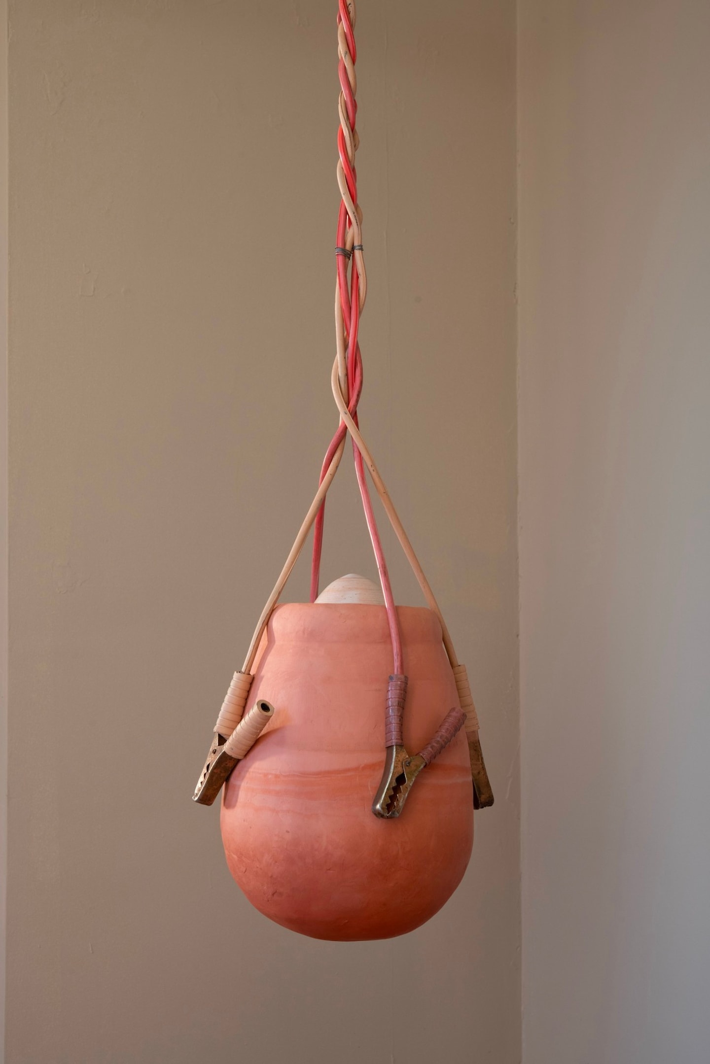 sculpture of a hanging jar made from ceramics in terracotta, reds, and tans