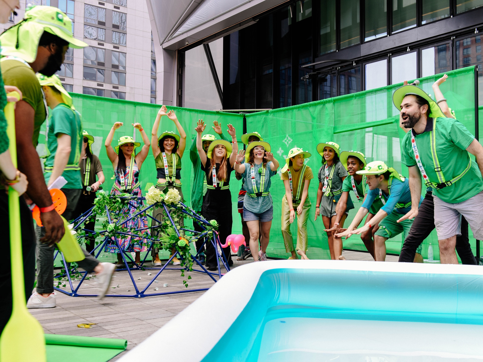 A group of participants in green hats, in front of a kiddie pool.