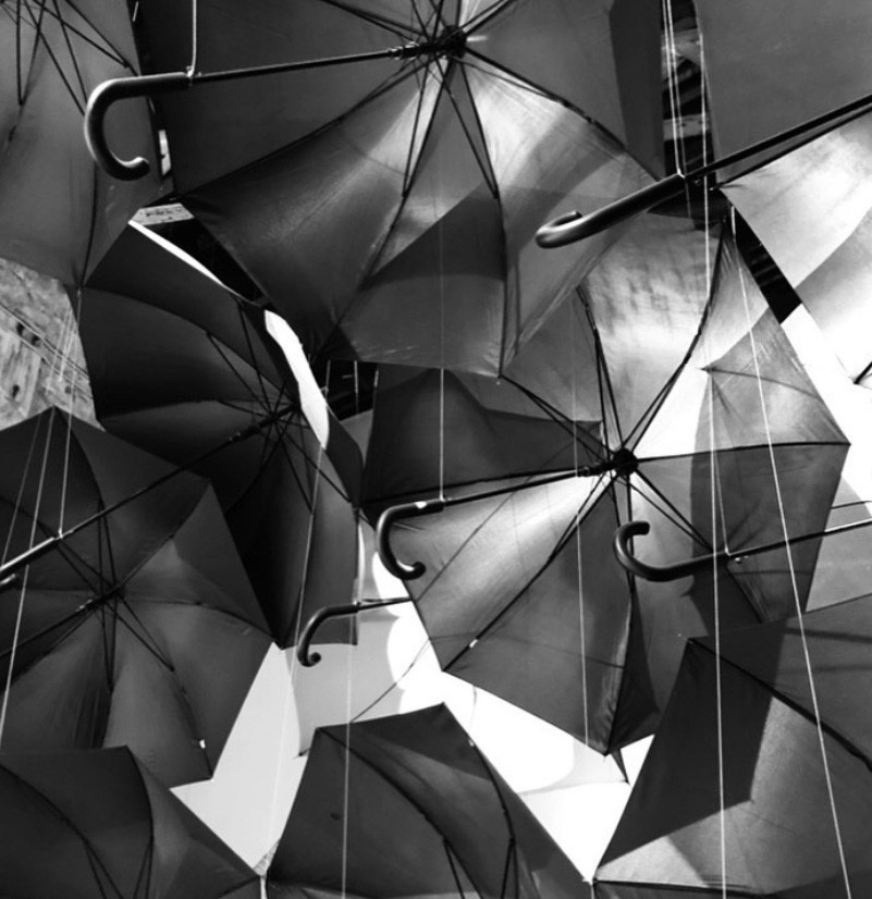 A black-and-white photo of a pile of open, overlapping umbrellas.