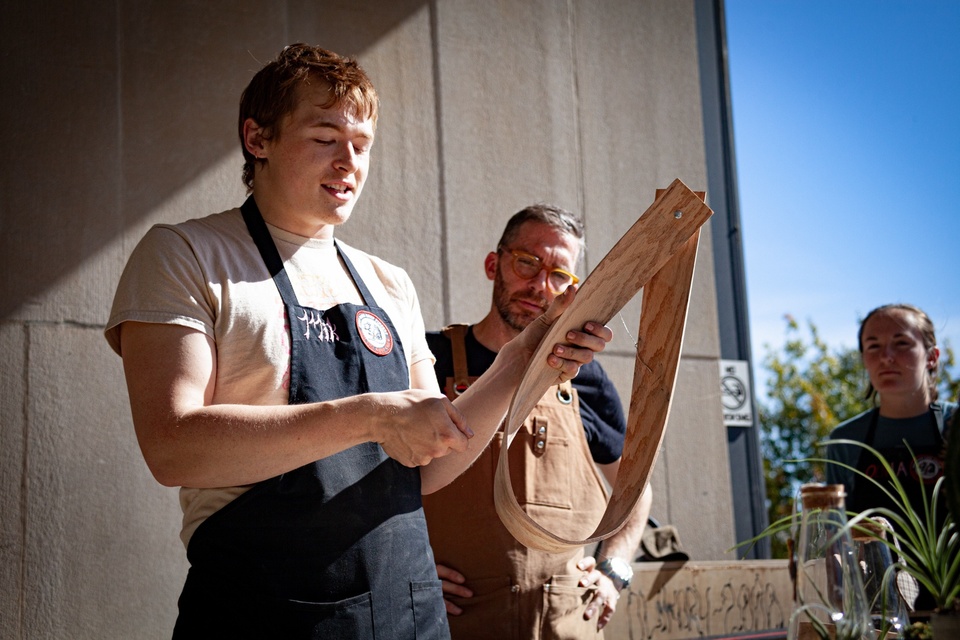 Student holds up a wood bent into a loop while Greg Cuddihee looks on