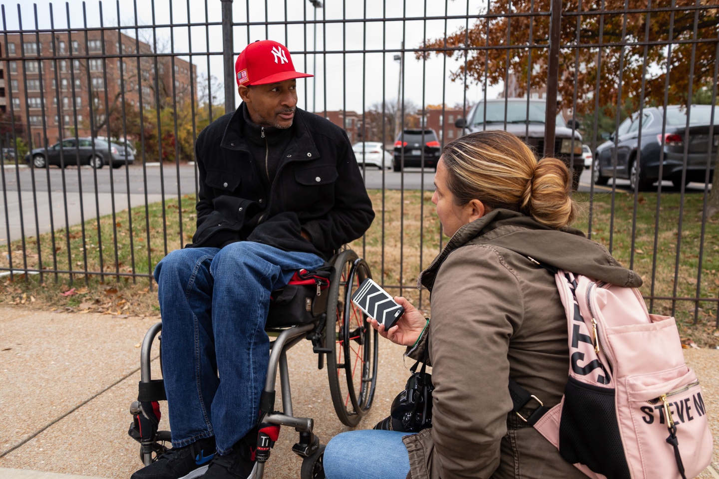 A woman with a microphone interviews a man in a wheelchair