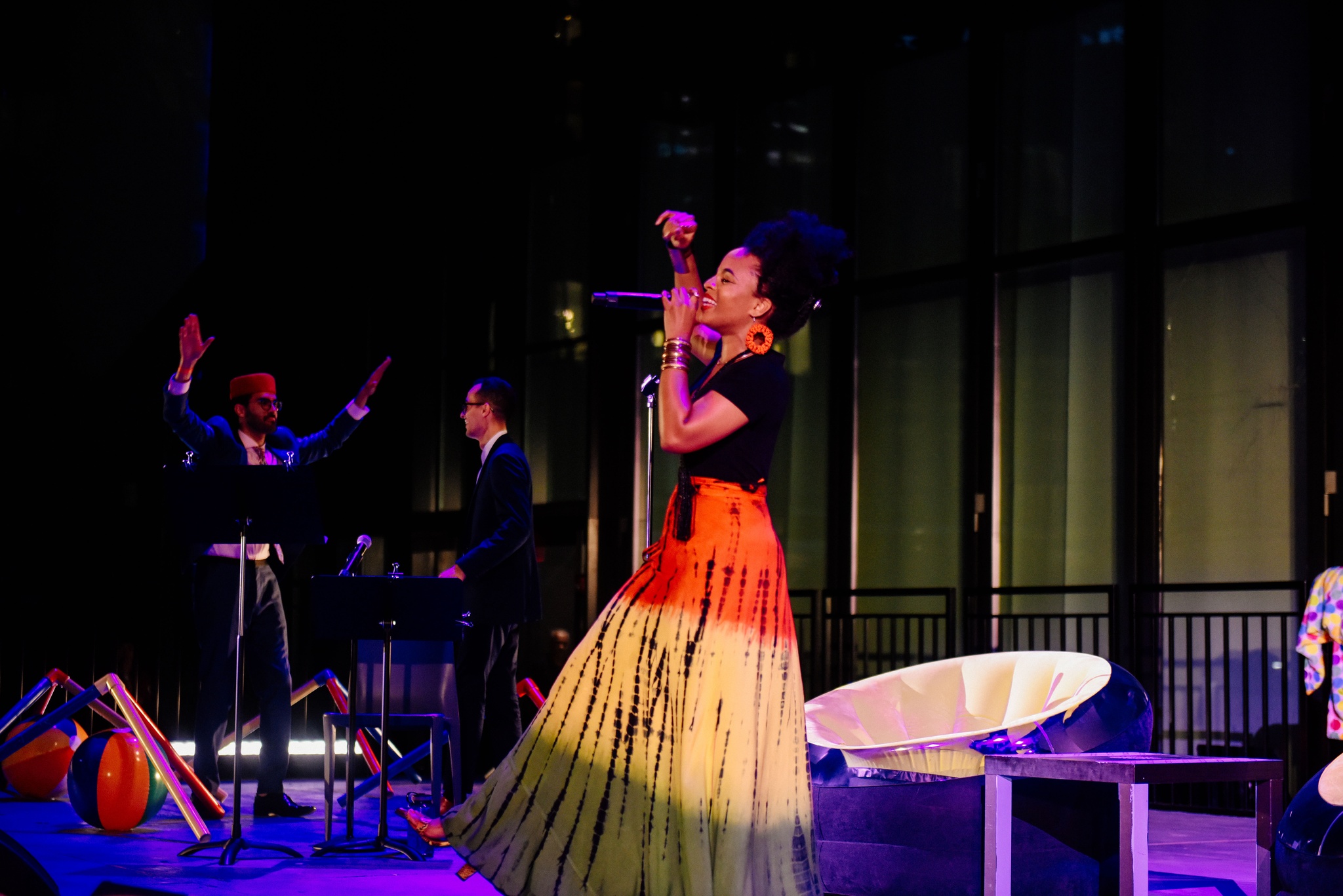 Woman singing on purple lit stage.