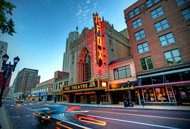 Midcentury style vertical theatre sign, lit up in red neon at dusk, outside the Fox Theatre in St. Louis.