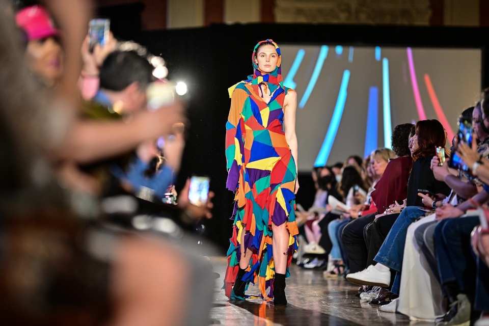 A model walking down the runway in a multicolored hooded dress