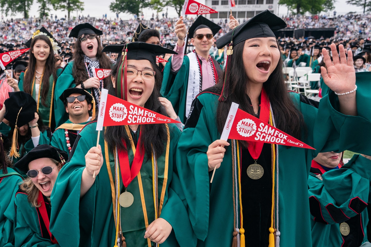 group of students waving Sam Fox School pennants at commencement