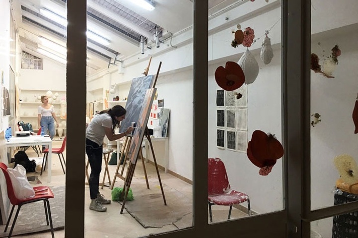 Two people working in an art studio making paintings and sculptures.