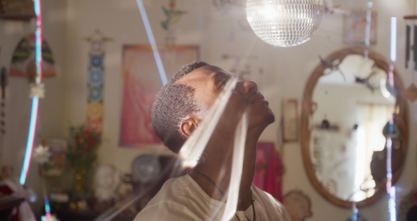 A young man standing beneath a mirror ball