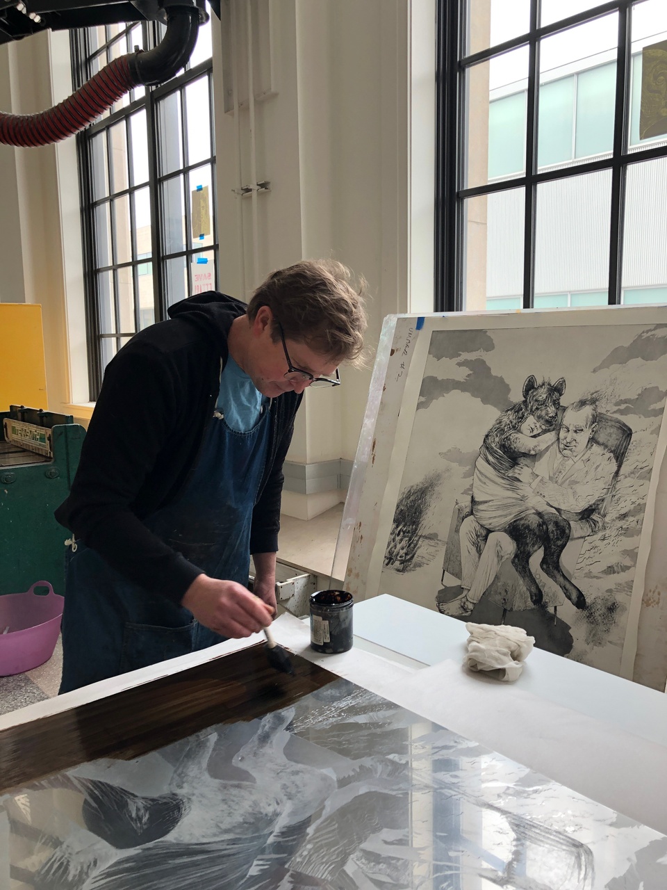 The master printer is painting a protective ground on an etching plate.