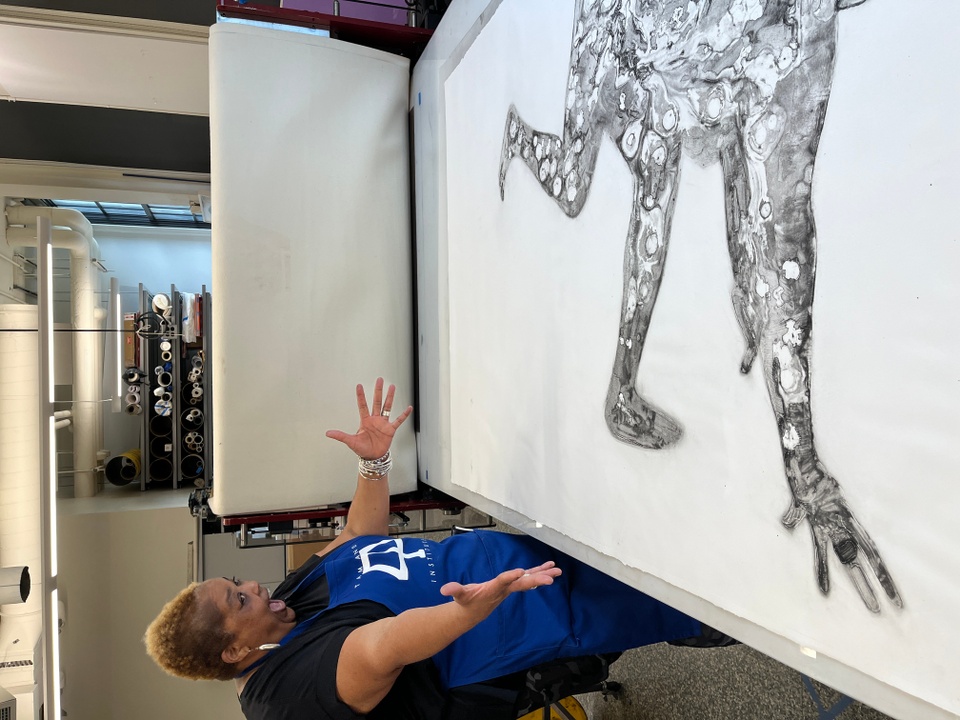 Artist gesturing "wow" at proof of new print on the etching press