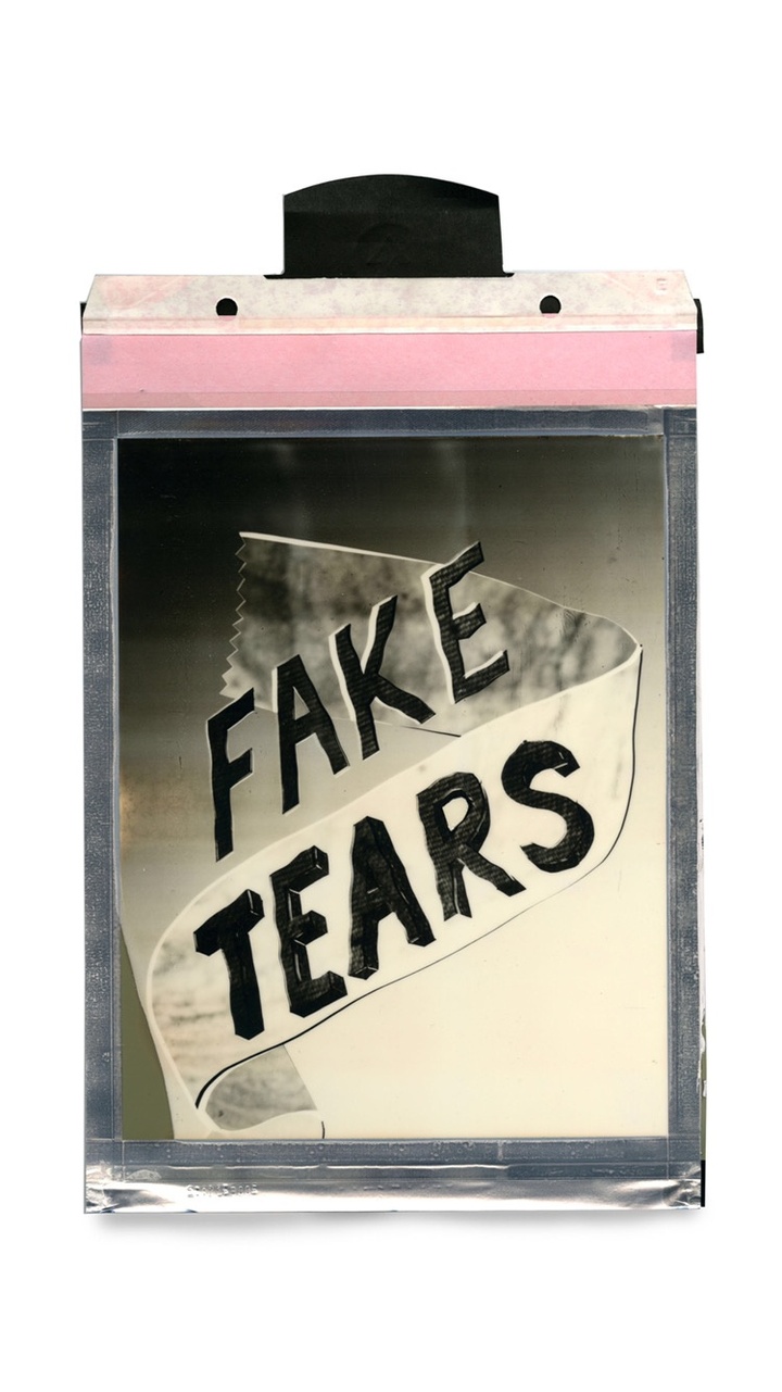 A polaroid of the text 'Fake Tears' with a ribbon over it