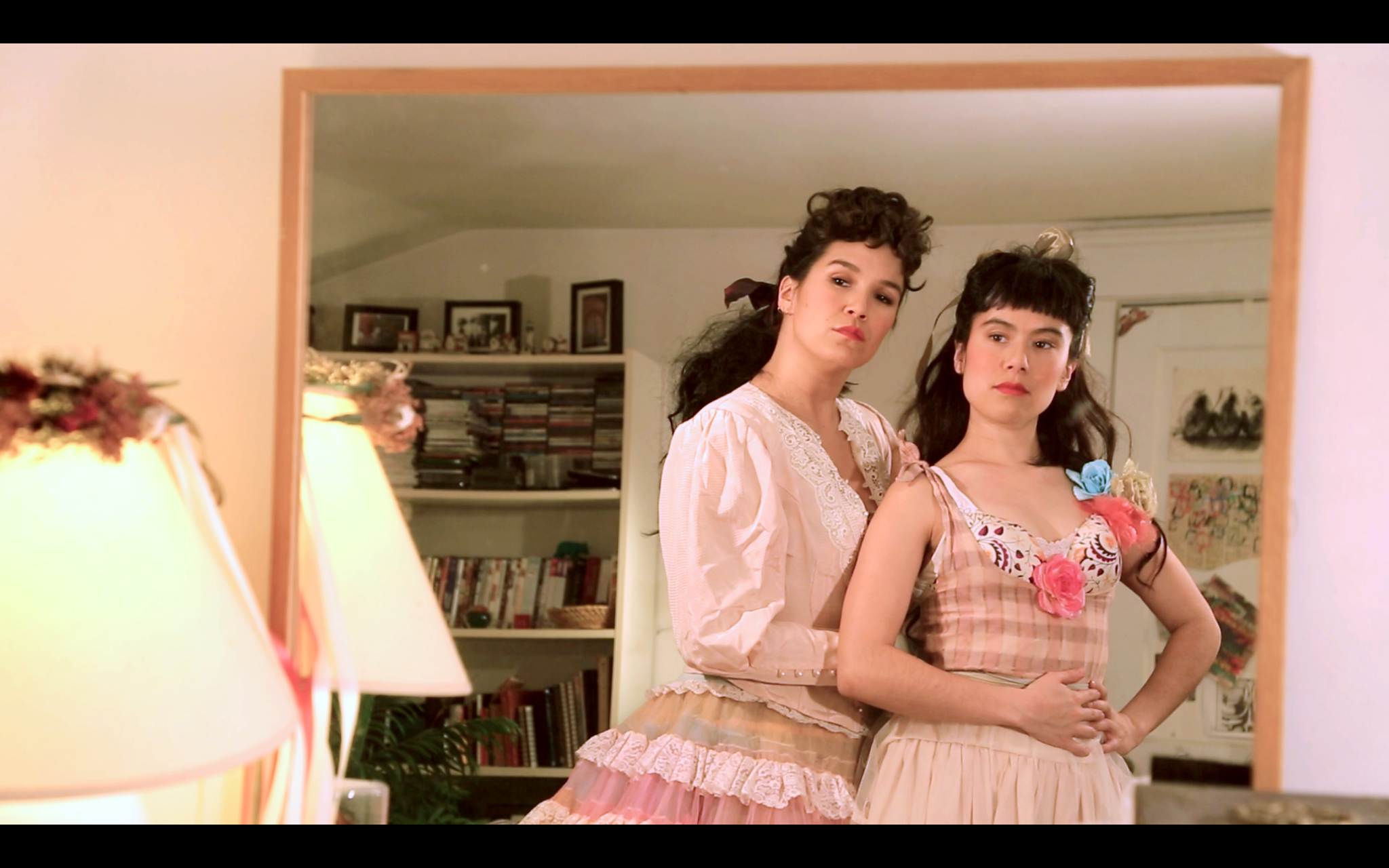 Maia and Zoe Chao standing in front of a mirror in a still from Open Call artist Maia Chao's video work What Draws Us Together, What Drives Us Apart