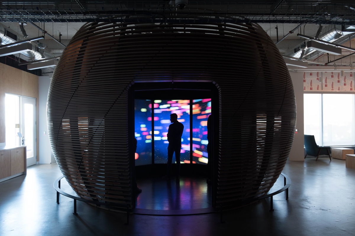 Silhouetted man standing in center of a large domed installation with colorful data visualization happening inside