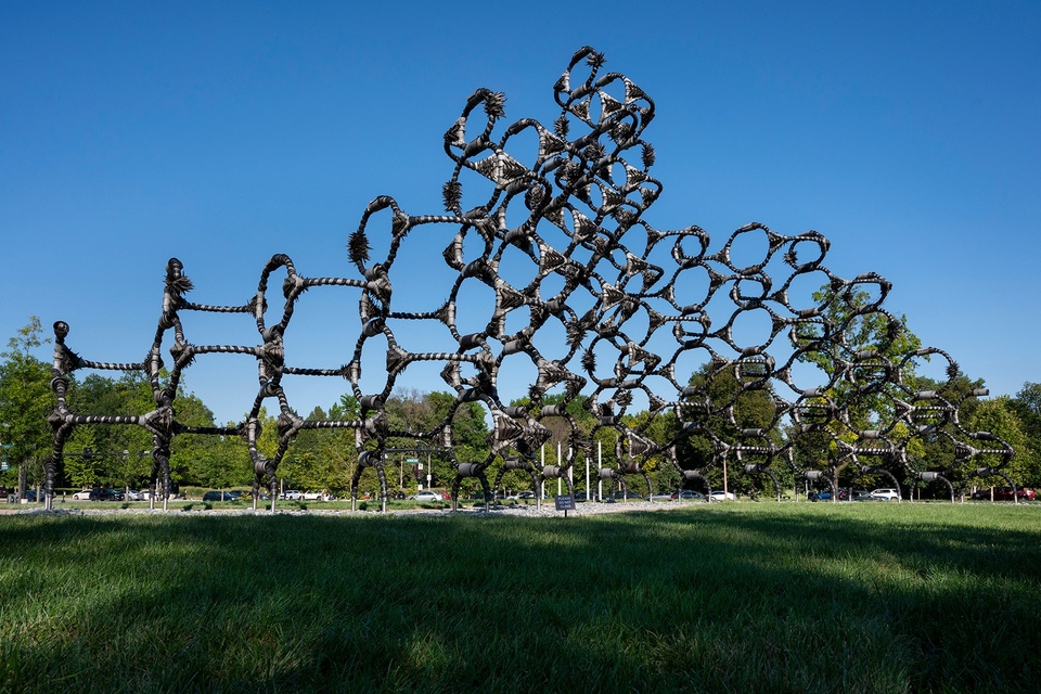 A large, outdoor sculpture composed of modules of circles and lines created from car tires