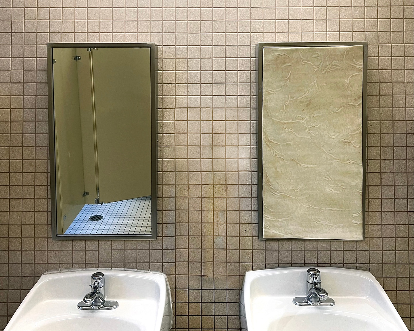 A photo of a bathroom wall with two sinks and two mirrors, but one of the mirrors is warped.