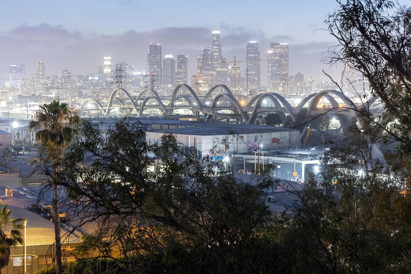 Color photo of Sixth Street Viaduct in Los Angeles with city skyline in the background.