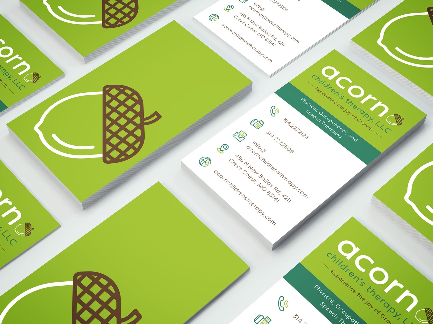 Series of business cards with lime green backs with drawing of an acorn in white and brown; the front side says acorn with additional info.