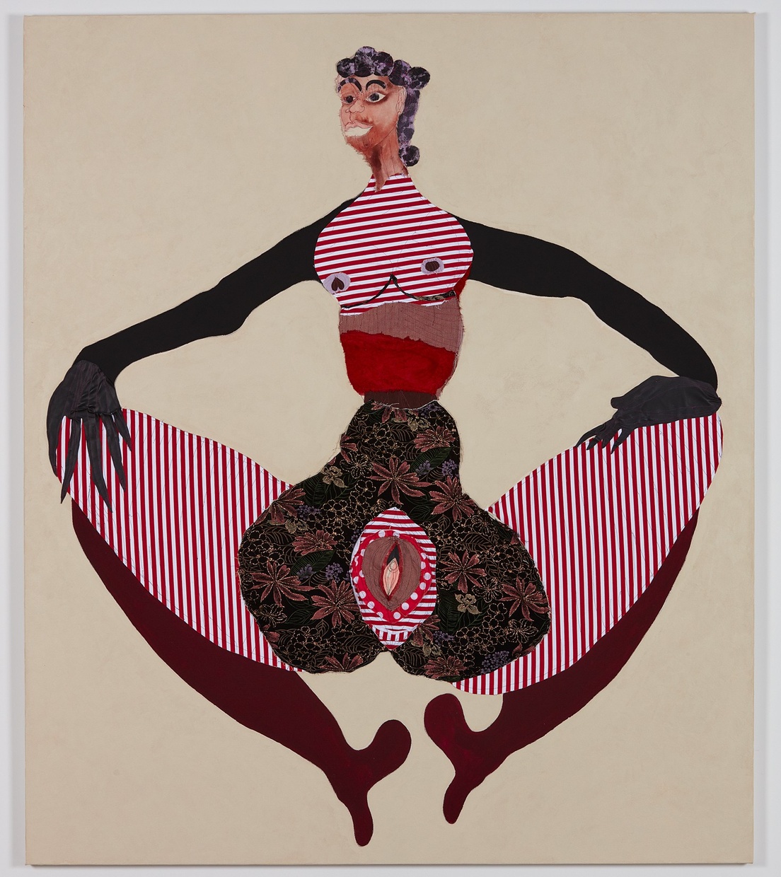 A large, abstract female figure made of different patterned material holding her knees apart, displaying her vagina. 