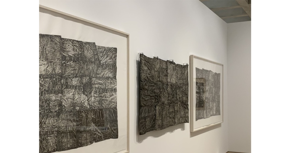 three large prints titled MASS made from folded shirts by artist Nick Cave on wall seen from an extreme angle
