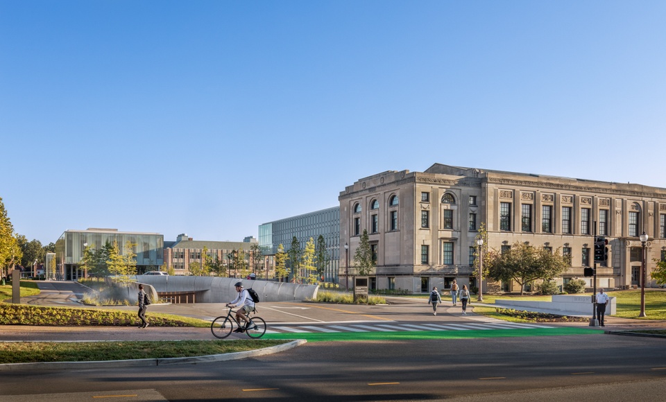 Beaux-arts style building next to a parking garage entrance and a wide bike trail painted bright green.