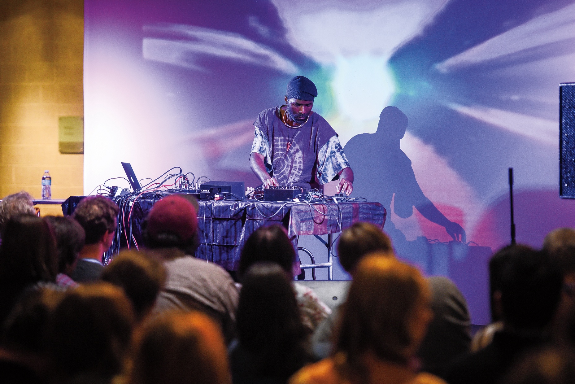 Photo of a man deejaying with purple and blue lights flashing around him.