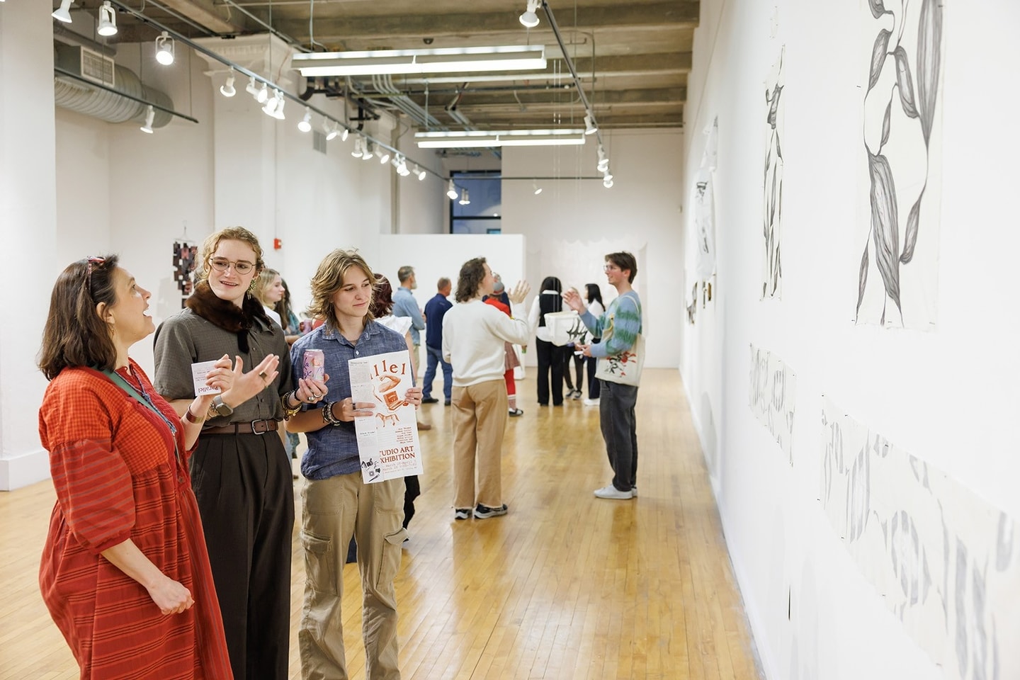 People standing and discussing the artwork on the wall in front of them in an art gallery.