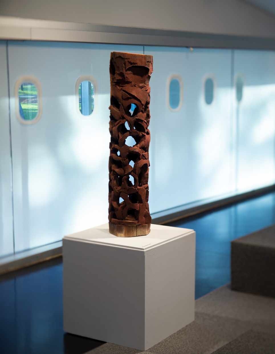 A vertically oriented sculpture on a plinth in a gallery.
