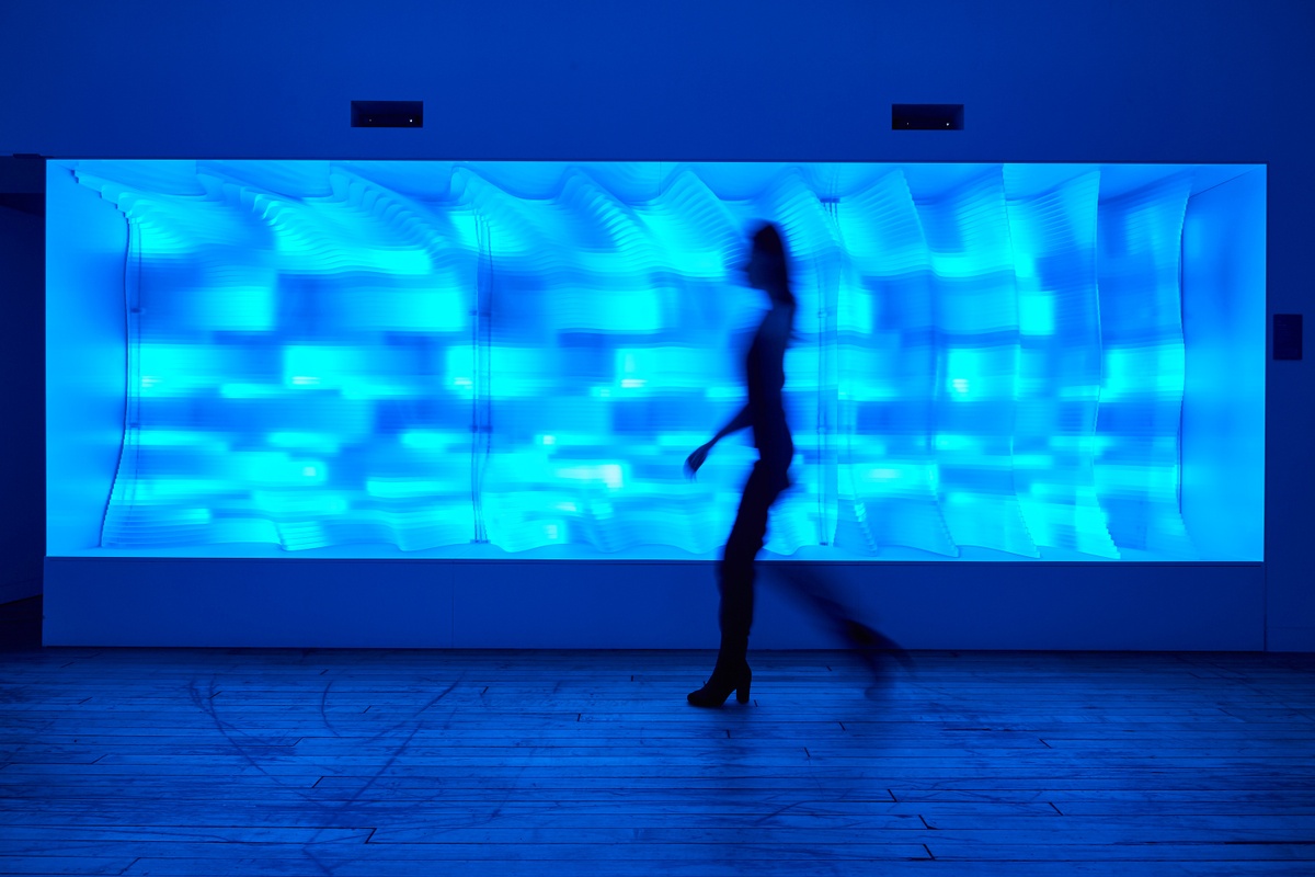 Blurred silhouette of person walking across The Passage, which glows in different shades of blue