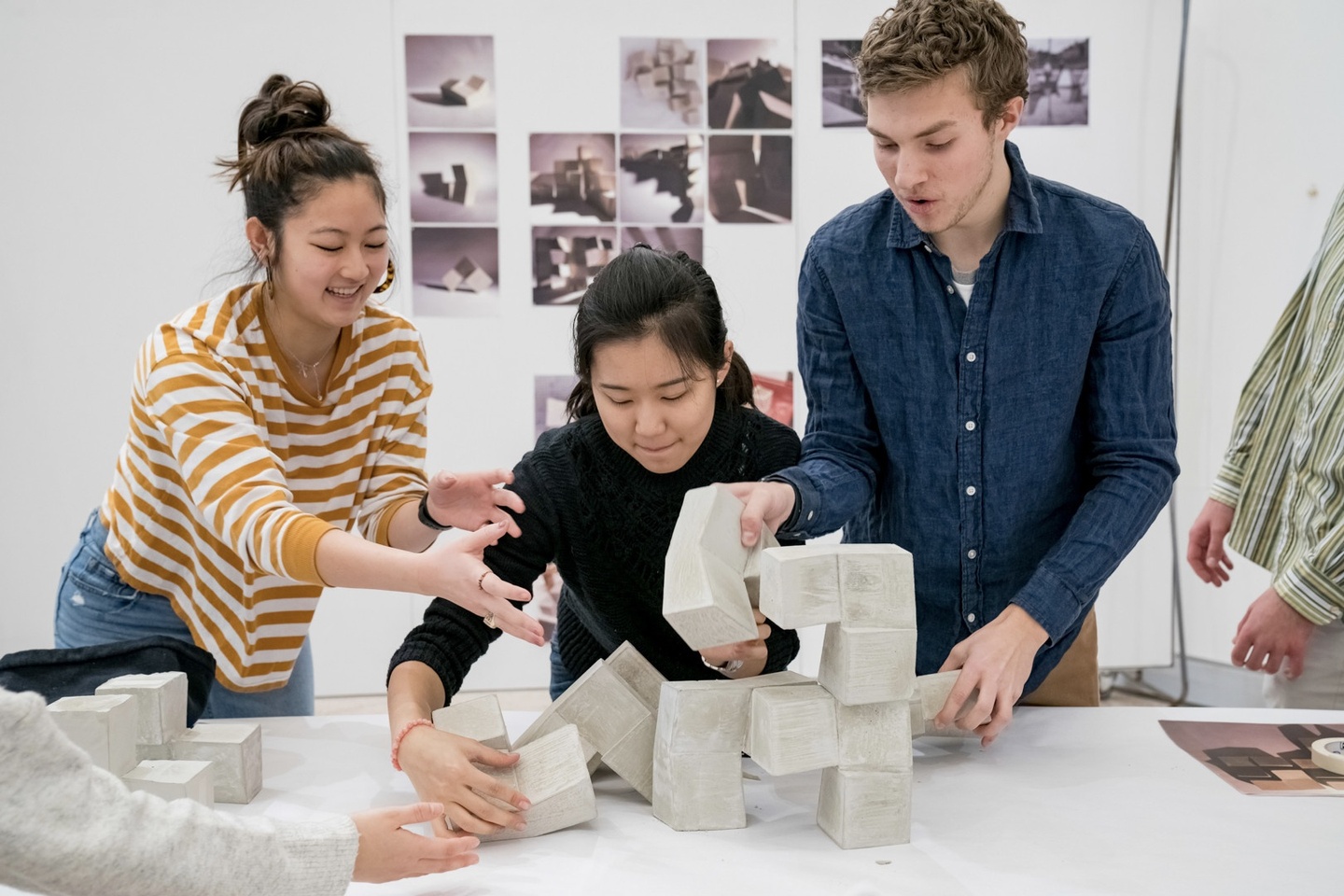 Three students arranging their modular assembly in cast concrete on a table.