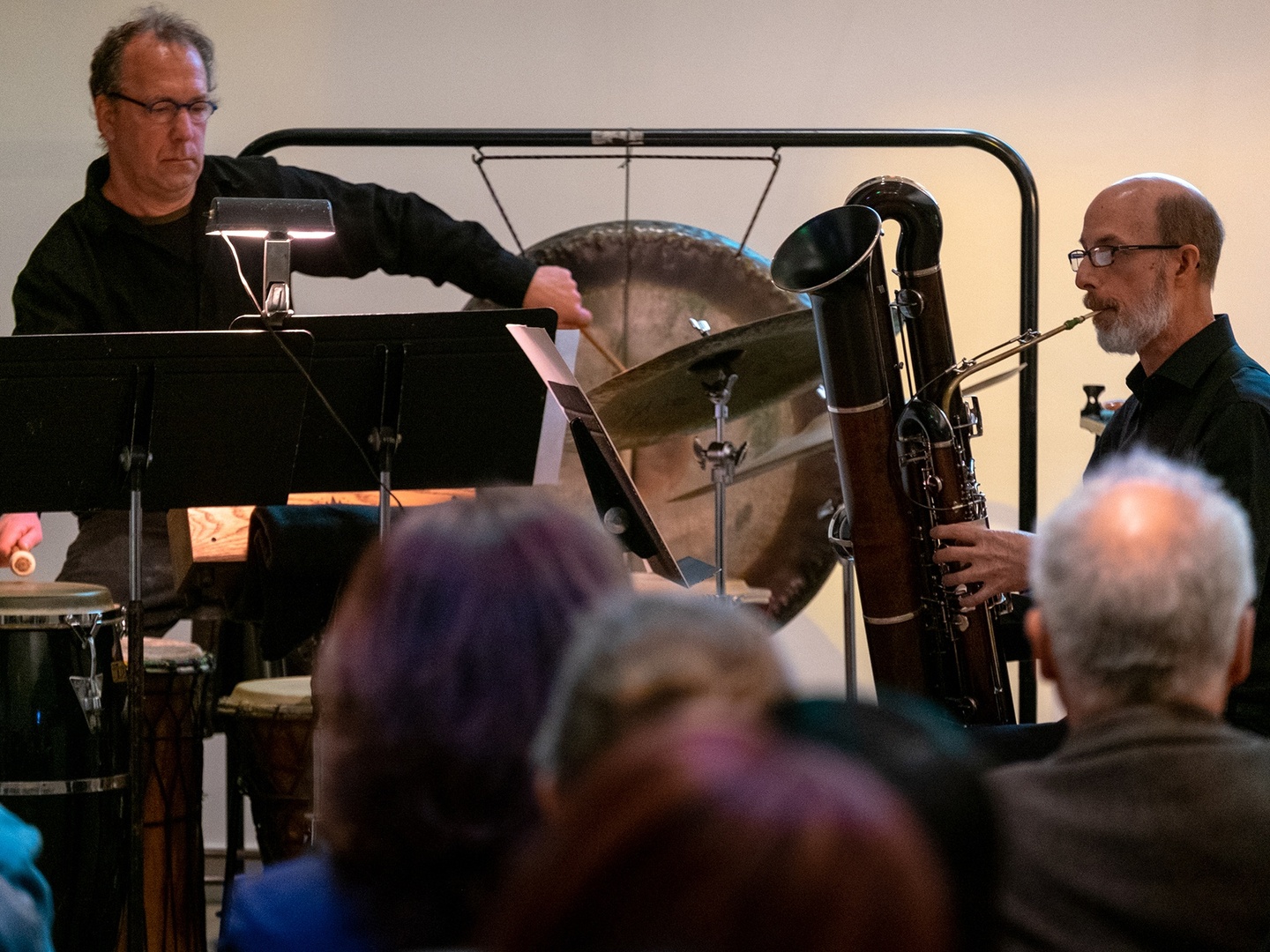 One man playing percussion and one playing a bassoon 