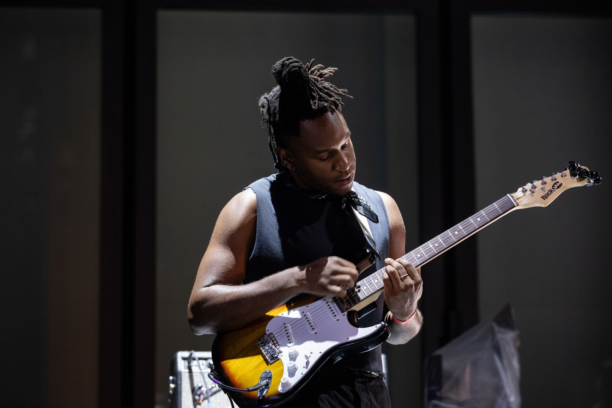 Man playing guitar on dramatically lit stage.