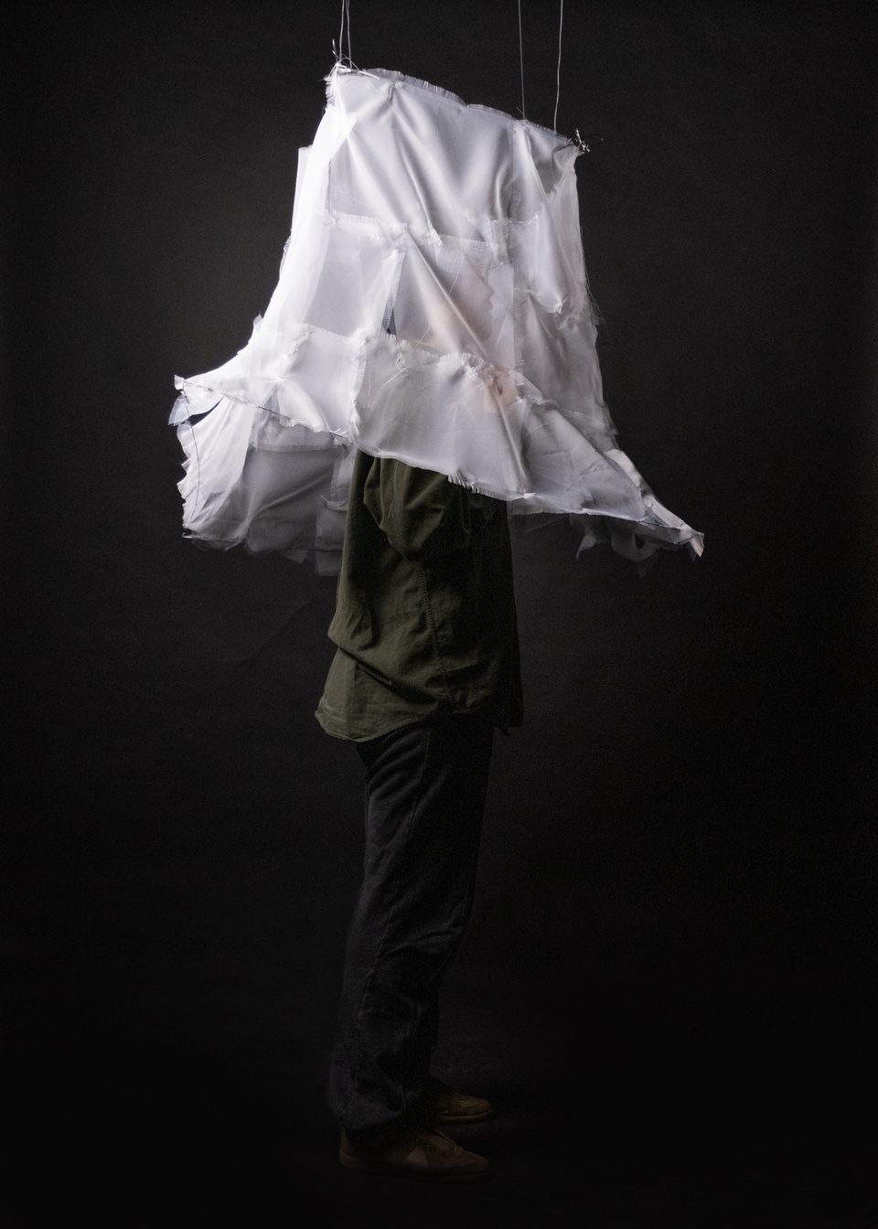 Photo of a draped white fabric hat over a black form.