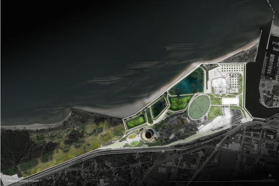 An architectural site plan showing a waterfront landscape development along a dark coastline. The highlighted site features green wetlands and retention ponds, curved pedestrian pathways, a large circular structure, a central oval lawn, and paved plazas bordering an adjacent town and marina.